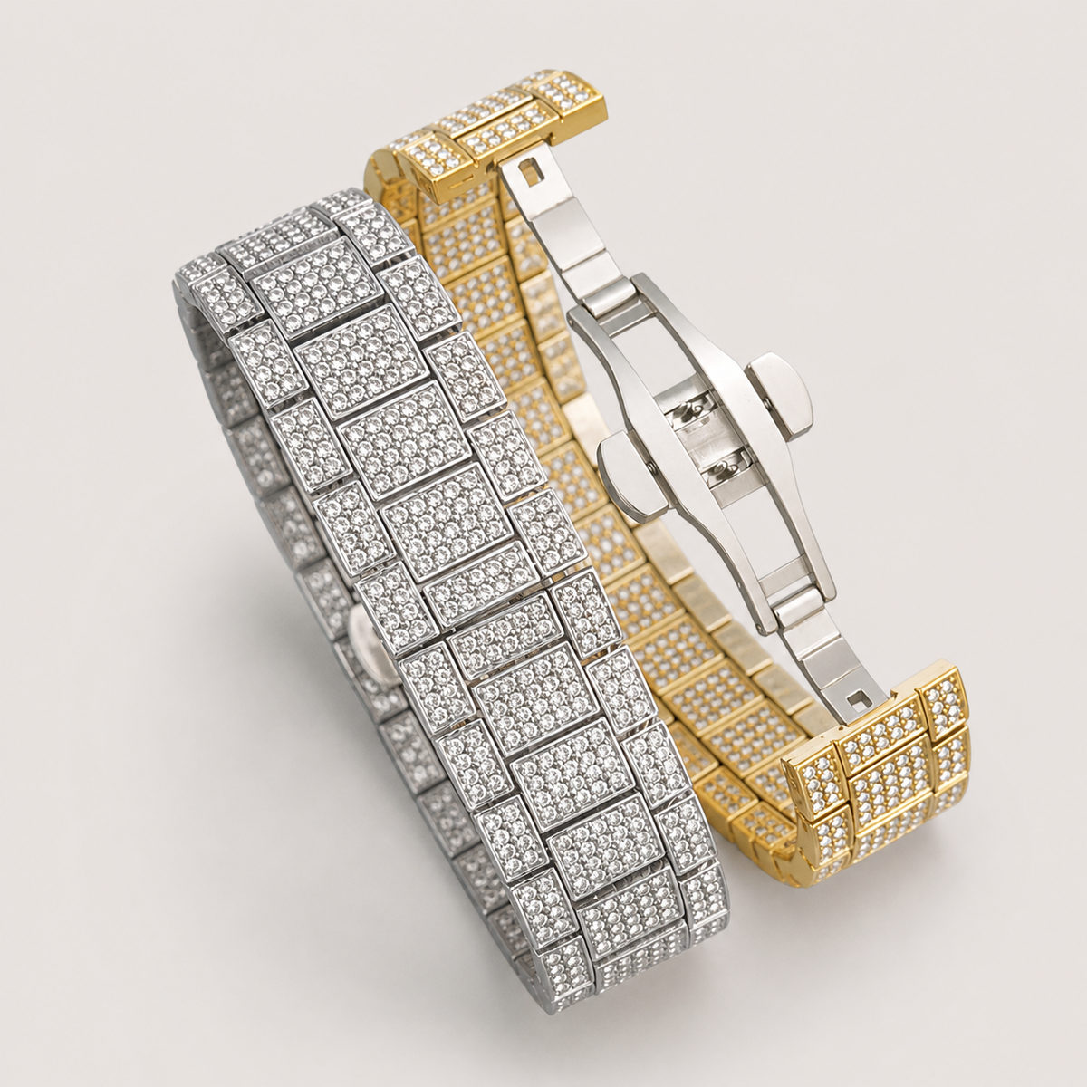 Silver-tone and gold-tone crystal-set watch bracelets with an open deployment clasp, close-up