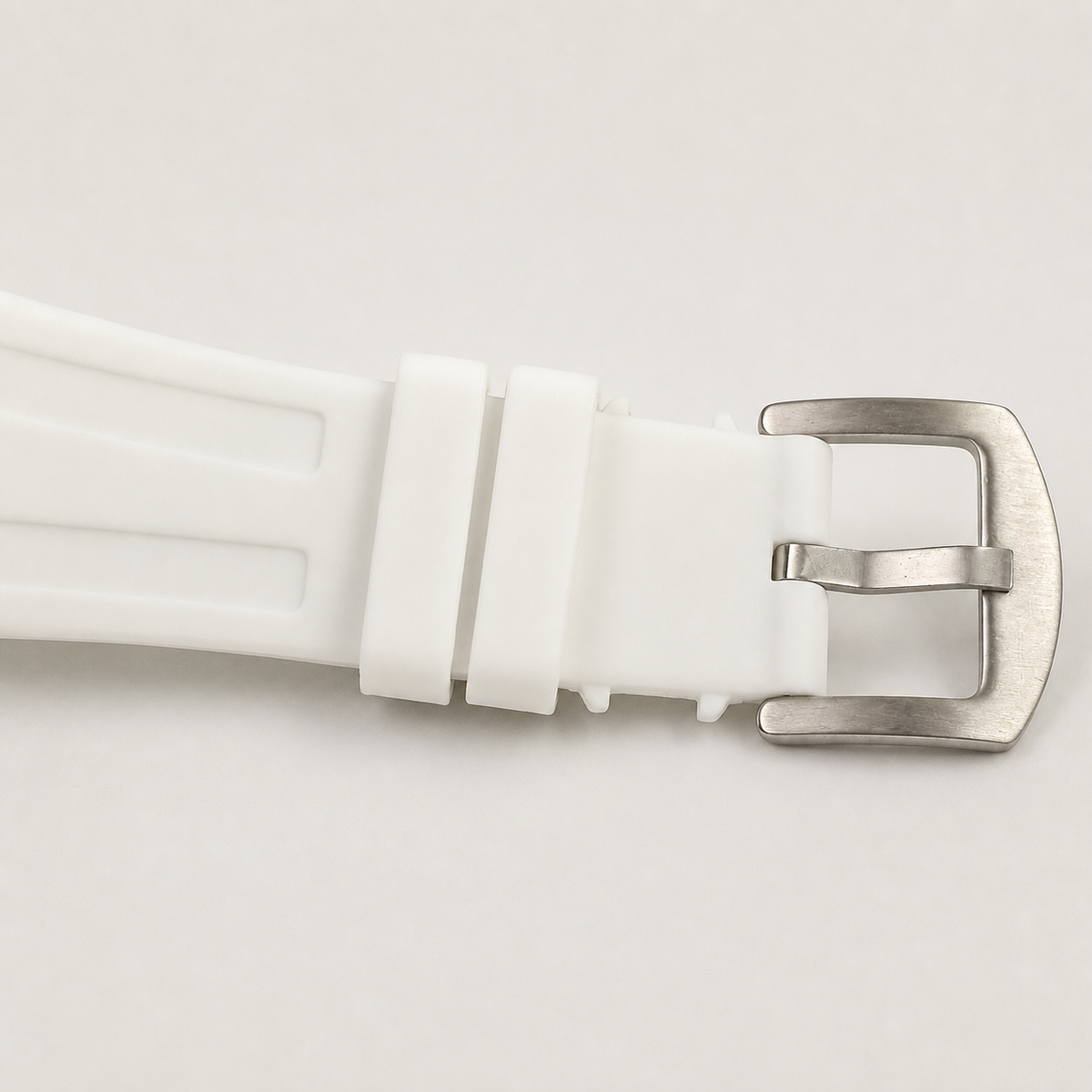 White silicone watch strap with silver buckle and keepers, close-up