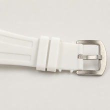 White silicone watch strap with silver buckle and keepers, close-up