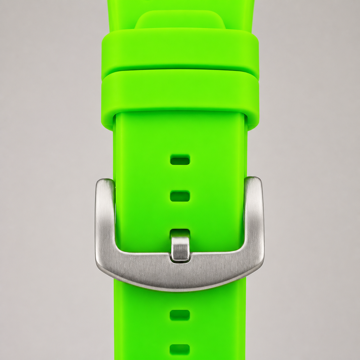 Lime-green silicone watch strap with silver buckle and keepers, close-up